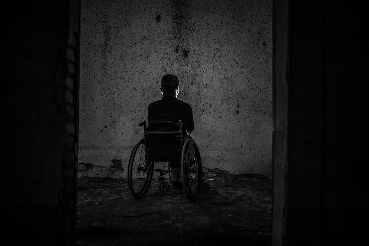 Person in a wheelchair viewed from behind in a dim room